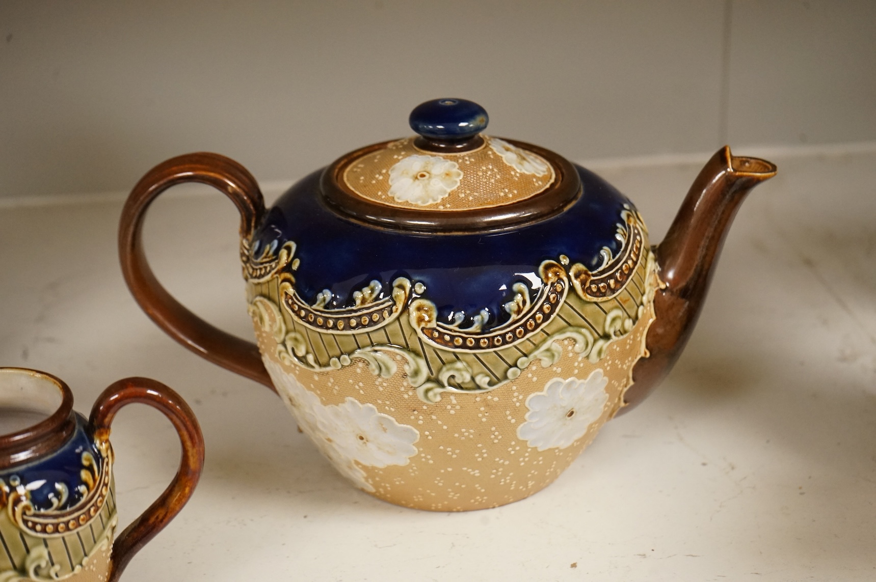 A small collection of Doulton Lambeth stoneware comprising, tea and coffee pots, two jugs and sugar bowl, largest 21cm high